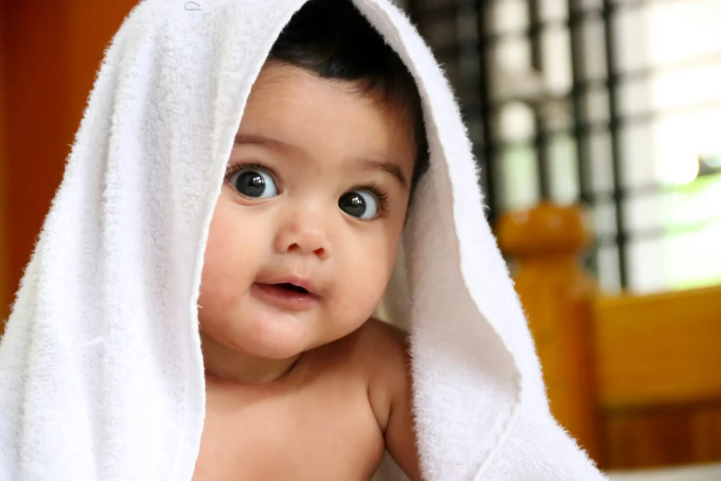 adorable baby with big eyes peeking out from a white towel, creating a charming and playful expression