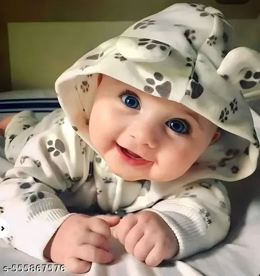 Adorable baby in a paw-print onesie, smiling widely with bright blue eyes, lying on a soft surface.